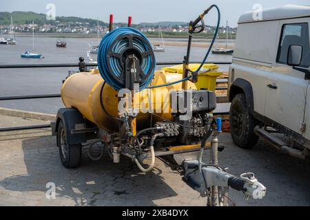 Conwy Wales Regno Unito 06-01-2024. Rimorchio giallo per lavaggio a pressione presso il porto con barche e veicoli commerciali sullo sfondo Foto Stock