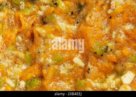 Impasto fresco e sano di carote e pezzi di frutta come banana e kiwi per preparare muffin dietetici dalla consistenza morbida e succosa. Foto Stock