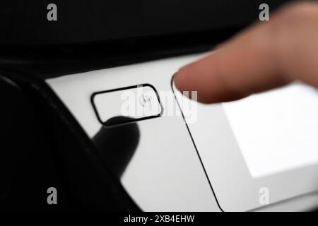 Premere il pulsante con il dito per accendere la fotocopiatrice e lo scanner. Primo piano del pannello di controllo della stampante laser per ufficio nero Foto Stock