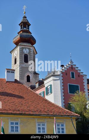 Primo piano di una torre della chiesa e degli edifici storici vicini sotto un cielo azzurro, la chiesa di Santa Caterina, Frohnleiten, Graz Foto Stock