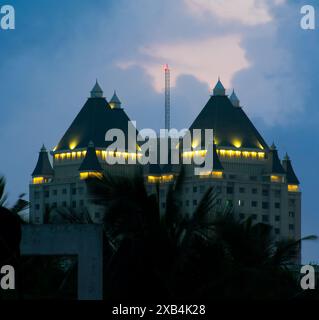 la sua impressionante fotografia cattura un grande edificio simile a un castello illuminato da luci calde contro il cielo crepuscolo più profondo. L'architettura unica, Foto Stock