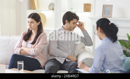 Uomo e donna frustrati che parlano con il terapista sul divano Foto Stock