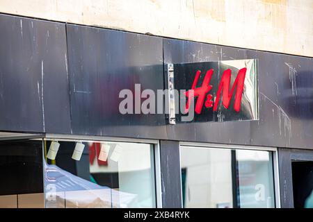 Cartellonistica, branding, logo e facciata del negozio di fronte a H&M. Foto Stock