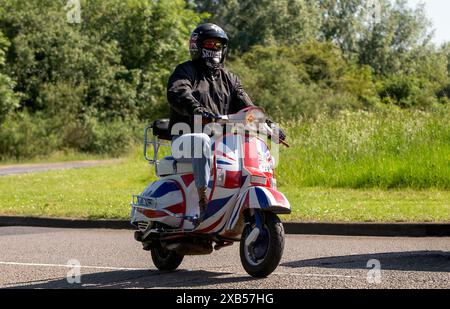 Stony Stratford, Regno Unito - 2 giugno 2024: 1997 Piaggio PX 200 e scooter su una strada di campagna britannica Foto Stock