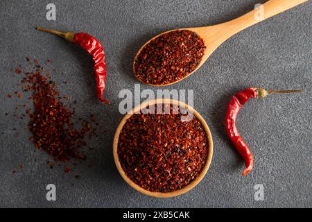 Peperoncino rosso. Peperoncini rossi in un recipiente di legno su sfondo grigio. Peperoncini secchi Foto Stock