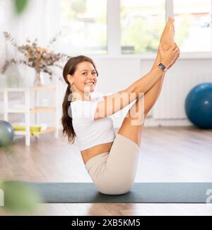 Insegnante esperta di club fitness esegue ubhaya padangushthasana Foto Stock