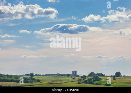 Fattoria e campi dell'Iowa sotto uno splendido paesaggio nuvoloso in un pomeriggio estivo di sole Foto Stock