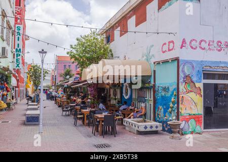 Splendida vista su una strada vivace con caffetterie all'aperto ed edifici colorati in una giornata di sole. Willemstad. Curacao. Foto Stock