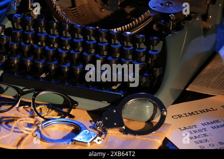 Macchina da scrivere retrò, polsini, occhiali da vista e fascicoli criminali sul tavolo, primo piano Foto Stock