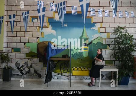 Atene, Grecia. 9 giugno 2024. Un votante si trova accanto a una cabina di votazione in un collegio elettorale decorato con bandiere greche. Gli elettori di 27 paesi dell'Unione europea si recano alle urne tra il 6 e il 9 giugno per eleggere i membri del Parlamento europeo. (Foto di Dimitris Aspiotis/Pacific Press) credito: Pacific Press Media Production Corp./Alamy Live News Foto Stock