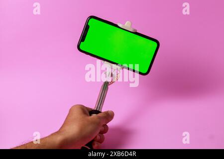 asta per selfie che viene solitamente utilizzata per foto di gruppo o selfie e anche per i vlog, è collegato un cellulare con uno schermo verde adatto per de Foto Stock