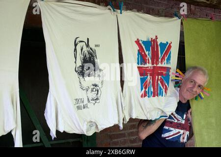 uomo maturo con le orecchie che intrattiene i bambini mentre si toglie il bucato per asciugare i vestiti sulla linea zala county ungheria Foto Stock
