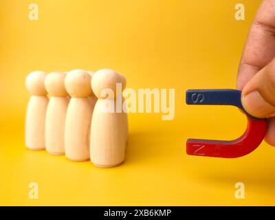 Figure di legno di persone e una calamita. Concetto di gestione del team. Risorse umane. Promuovi. Scegliere un nuovo leader e assumere dipendenti per lavorare. Servizi di caccia alla testa. Licenziamento dei dipendenti. Foto Stock