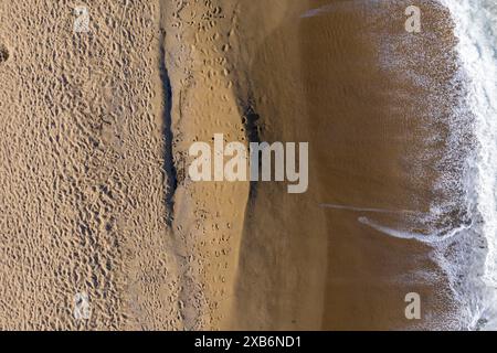 Vista aerea di una remota spiaggia sabbiosa e delle onde del mare con drone Foto Stock