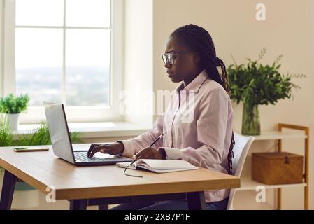 Commercialista afroamericana che lavora su un portatile in ufficio. Foto Stock