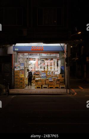 Una donna in piedi di notte di fronte ad una libreria Foto Stock