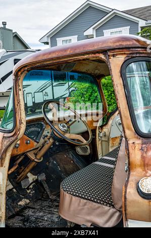 Un pick-up vintage arrugginito parcheggiato di fronte a una casa rustica Foto Stock