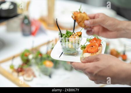 catering. Mani che mettono l'insalata con gamberi e bruschette con salmone su un piatto, deliziosi stuzzichini a mano Foto Stock