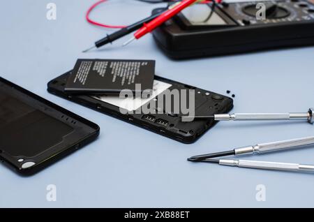 Smartphone smontato, processo di sostituzione della batteria. Il coperchio posteriore dello smartphone è stato rimosso, rivelando la batteria e i componenti interni Foto Stock
