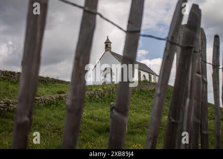 Recinzione in legno con chiesa d'epoca arroccata sulla sommità Foto Stock