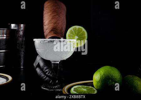 Barman che serve un margarita guarnito con fette di lime Foto Stock
