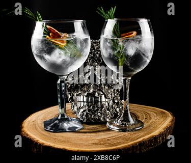 Due bicchieri da vino con ghiaccio, rosmarino e acqua su un tavolo Foto Stock