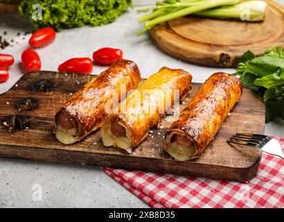Un tagliere con quattro hot dog e verdure nelle vicinanze Foto Stock