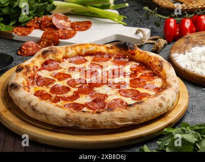 Una pizza al peperoni su un tagliere di legno Foto Stock