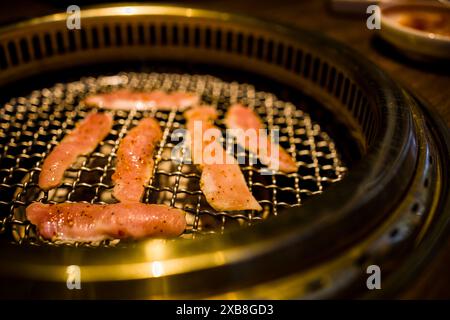 Strisce di pancetta sfrigolanti su un'ampia teglia per barbecue Foto Stock