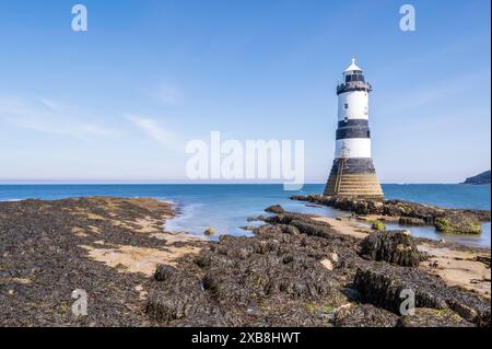 Faro sul bordo di un promontorio roccioso. Il faro si trova a Penmon Point, Angelsey, nel Galles settentrionale. La giornata è soleggiata Foto Stock