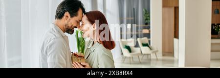 Una donna rossa e un uomo barbuto condividono un tenero bacio in un soggiorno contemporaneo, circondato da un arredamento moderno. Foto Stock