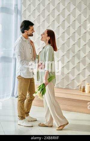 Un uomo barbuto e una donna rossa stanno insieme in un appartamento moderno, trasudando amore e connessione. Foto Stock