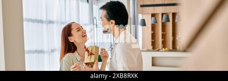 Una donna rossa e un uomo barbuto stanno insieme nel loro appartamento moderno. Foto Stock