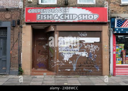 Un negozio di chip chiuso a Londra con graffiti disordinati sulle persiane per finestre. Foto Stock