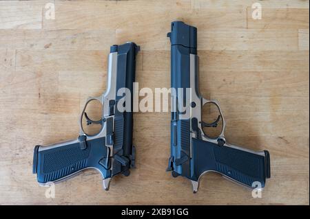 Un paio di classiche pistole polizia da 9 mm su un tavolo di legno. Uno con freno a bocca e compensatore e l'altro senza Foto Stock