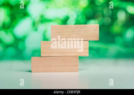 3 rettangolo impilabile blocchi di legno vuoti sul tavolo con sfondo verde naturale sfocato per testo o lettere del cliente. Idea di ambiente, energia o. Foto Stock