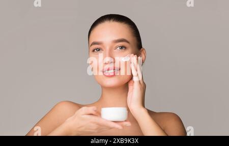Donna che applica Hydrating Cream al viso Foto Stock