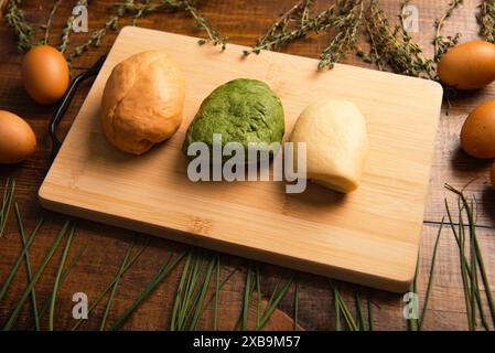 Una scena affascinante con vivaci impasti di pasta su un tavolo, circondati da uova ed erbe aromatiche, in un ambiente delizioso Foto Stock