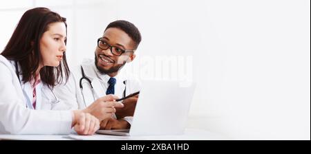 Due medici consulenza, utilizzando laptop in ufficio Foto Stock