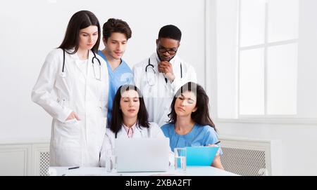 Multirazziale medici guardando portatile per lavorare insieme in clinica Foto Stock