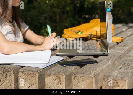 Giovane ragazza universitaria all'inizio delle lezioni, prendendo appunti nel campus. Mani degli studenti, notebook, vita accademica, tecnologia, ambiente educativo Foto Stock