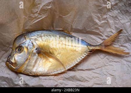 Pesce vomer affumicato su pergamena sgusciata sul tavolo. Foto Stock