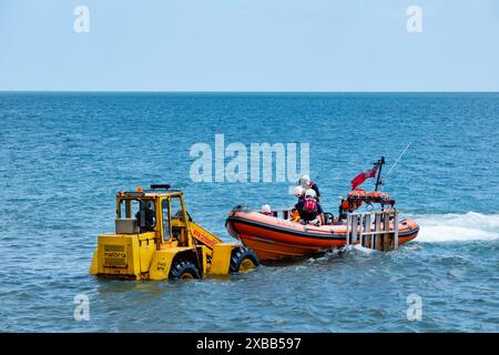 La scialuppa indipendente Sandown e Shanklin torna a terra e viene aiutata a sbarcare da un trattore che tira un rimorchio a cui è collegata la barca Foto Stock