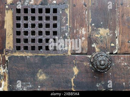 Francia, Parigi - 3 gennaio 2024 - porta medievale antica con un piccolo spioncino. Antica porta in legno marrone scuro e piccola finestra con griglia in ferro, spazio copia, se Foto Stock