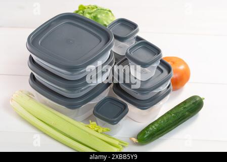 Una pila di contenitori di plastica e verdure crude sul tavolo. Stoccaggio di verdura e frutta in contenitori di plastica Foto Stock