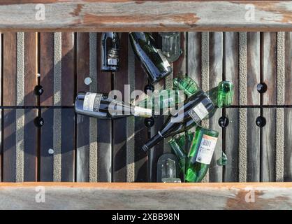 Francia, Parigi - 3 gennaio 2024 - Vista superiore delle bottiglie di birra e vino sono state lasciate sul pavimento accanto alle panchine di legno sul Pont des Arts Light e Sha Foto Stock