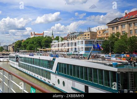 Bratislava. Slovacchia, 23-05-24. Barche ormeggiate lungo il Danubio con il castello di Bratislava in lontananza. Questo è un luogo popolare per le navi da crociera Foto Stock