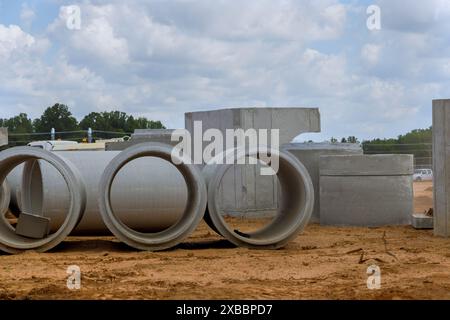 Pila di pozzi di drenaggio in calcestruzzo prima dell'installazione in cantiere Foto Stock