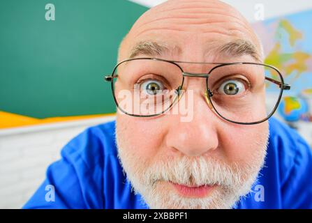 Primo piano ritratto di un divertente insegnante di scuola maschile in classe. Torna a scuola. Docente sorpreso o professore di occhiali durante la lezione. Apprendimento, istruzione Foto Stock