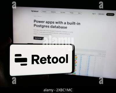 Persona che possiede uno smartphone con il logo della società di sviluppo software statunitense Retool Inc. Davanti al sito Web. Mettere a fuoco il display del telefono. Foto Stock